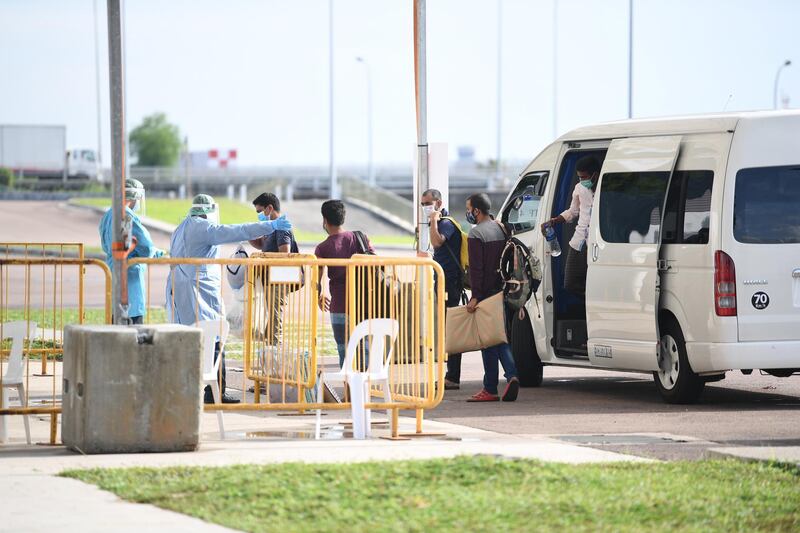 A handout photo made available by the Executive Committee for Changi Exhibition Centre Facility shows COVID-19 patients alighting a van before entering a community isolation facility at the Changi Exhibition Centre in Singapore. Singapore has seen a surge in the number of cases, with a majority of patients being work pass holders staying in foreign worker dormitories. To cope with the surge, Singapore has set up community isolation facilities with a capacity of over 41,000 beds.  EPA