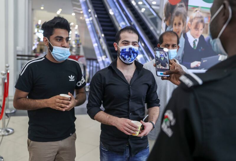 People go through the new EDE scanner system at Deerfields Mall, which instantly detects whether or not an individual has Covid-19, and reveals the result on a handheld receiver in Abu Dhabi. Khushnum Bhandari / The National