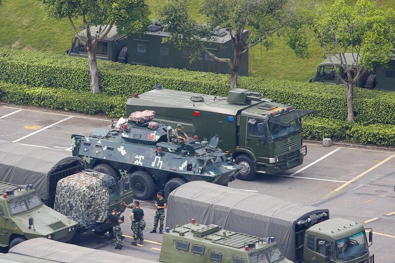 Chinese servicemen stand between military vehicles. Reuters