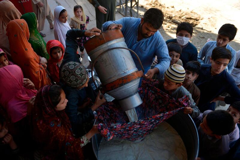 A milkman pours milk into a pot before delivering to their customers in Rawalpindi.  AFP