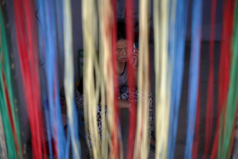 Recycling worker Gu Zhaofang is seen behind a blind as she speaks on her mobile phone at her tenement house at Dongxiaokou village. Kim Kyung-Hoon / Reuters