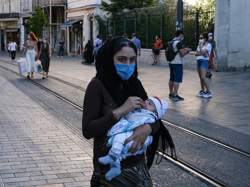 A Syrian refugee carries her baby amid the ongoing coronavirus pandemic, in Istanbul, Turkey.  EPA