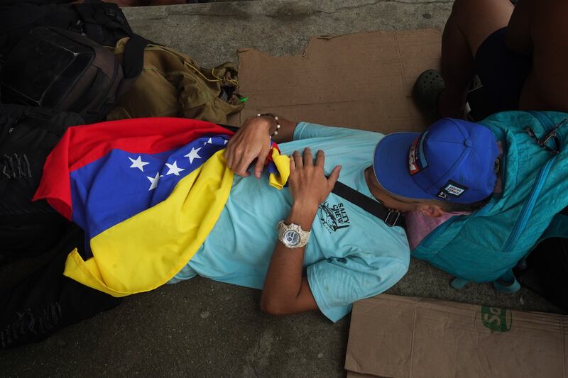 A migrant holds a Venezuelan flag as he naps at a sports centre upon his arrival in Huixtla. AP