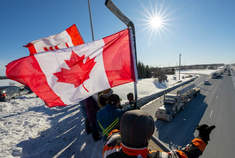 Supporters wave flags on a bridge as the convoy makes its way to Parliament Hill in Ottawa. AP