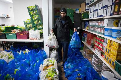 Elyas Ismail, founder of the Newham Community Project food bank, organises food packages ahead of their collection by international students, in east London on February 16, 2021. "It's hard to buy food, the prices are so much higher than in India": without work or state aid, young foreign students, like Jay Patel, came to the United Kingdom to realise their dreams are plunged into poverty because of the pandemic. Despite the rain, dozens of young people like him, hoods on their heads and shopping bags in their hands, congregate in front of the small room of the Newham Community Project association, in East London, to collect rice, vegetables and other foodstuffs. The Newham Community Project, in partnership with Abdullah Aid, provides a weekly food bank service where food and essentials are provided to over 1000 students every week. / AFP / TOLGA AKMEN / TO GO WITH AFP STORY by Charlotte DURAND
