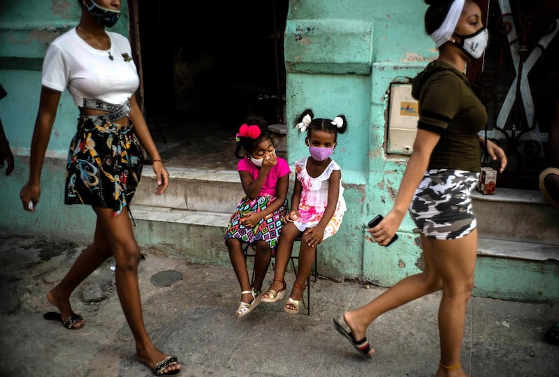 Wearing masks as a precaution against the spread of the new coronavirus Angelica Victoria, centre left, and Thalia Oneida, wait for their parents sitting on a chair in Havana, Cuba. AP Photo