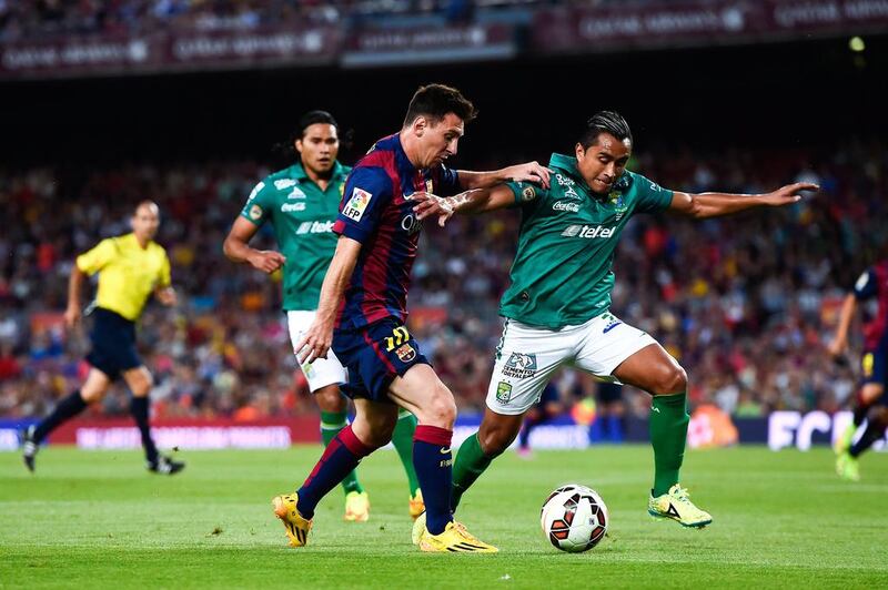 Lionel Messi of Barcelona competes for the ball with Edwin Hernandez of Leon during their friendly on Monday. David Ramos / Getty Images 