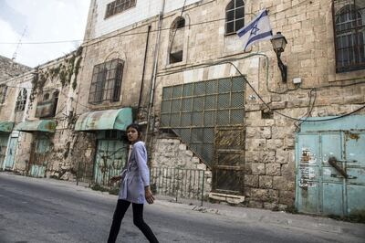 A Palestinian school girl walks along a Hebron street whose Palestinian shops have long since been welded shut by the Israeli military .There are 800 illegal settlers that live among the 200,000 Palestinians in the area .(Photo by Heidi Levine for The National).