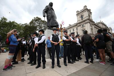 Police stand around the Winston Churchill statue ahead of a rally at the Nelson Mandela statue in the square, to commemorate George Floyd, on the day of his funeral, in Parliament Square, London, Tuesday June 9, 2020. The recent death of George Floyd who died after a U.S. officer pressed his knee into his neck, has prompted investigations into the lorded promotion of many historical figures who gave money to philanthropic enterprises, gave their names to British city areas, statues and landmarks, but gained much of their wealth from the slave trade. (Jonathan Brady/PA via AP)