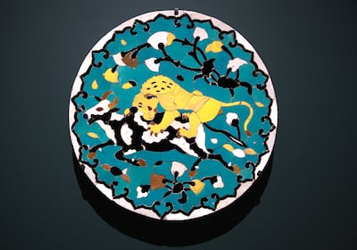 On display the exhibition, this 17th century ceramic mosaic from Iran is a roundel with a lion attacking a bull. Victor Besa / The National