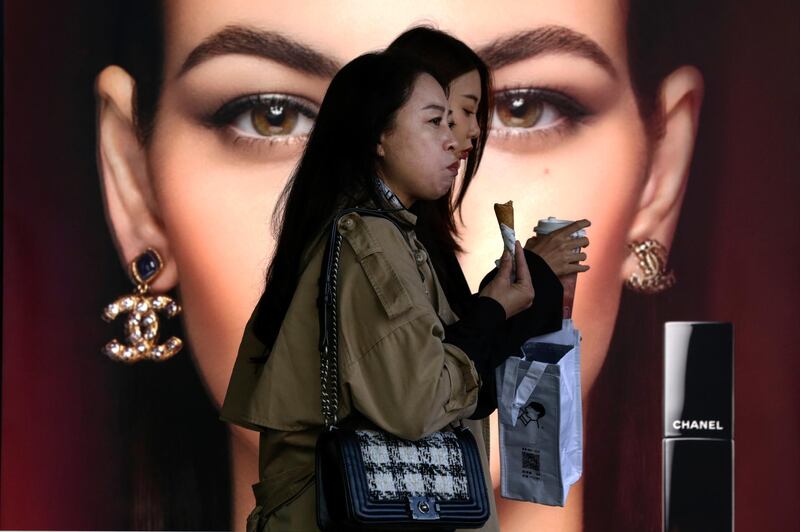 FILE - In this Oct. 19, 2020, file photo, women eating snack walk by a Chanel cosmetic shop at the capital city's popular shopping mall in Beijing. Chinaâ€™s economy grew 2.3% in 2020 as a recovery from the coronavirus pandemic accelerated while the United States, Europe and Japan struggled with disease flare-ups. (AP Photo/Andy Wong, File)