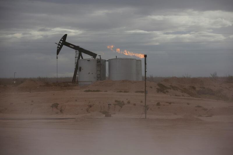 FILE PHOTO: Dust blows around a crude oil pump jack and flare burning excess gas at a drill pad in the Permian Basin in Loving County, Texas, U.S. November 25, 2019.REUTERS/Angus Mordant/File Photo