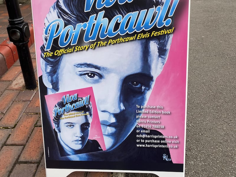 A street poster advertises the book 'Viva Porthcawl', the official story of the Porthcawl Elvis Festival.
