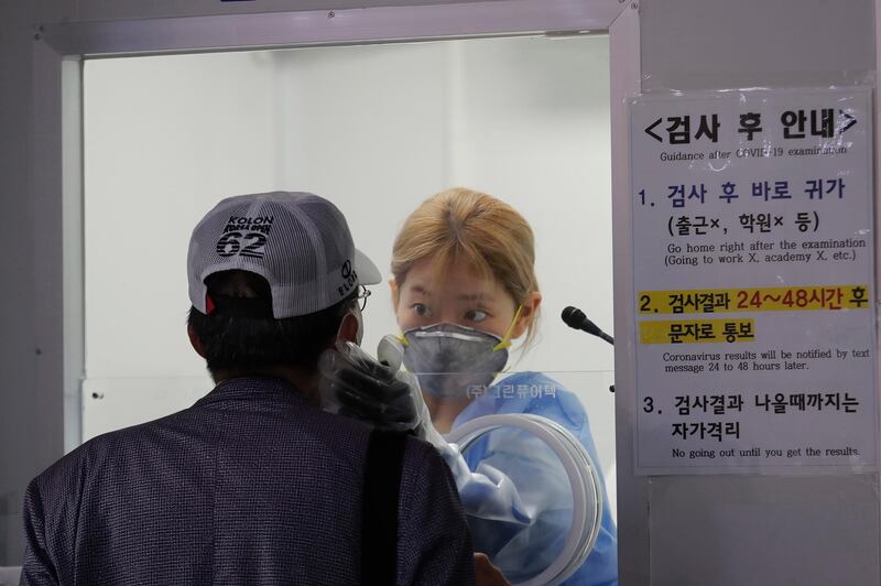 A medical worker in a booth takes samples from a man for a COVID-19 test at a makeshift clinic in Seoul, South Korea, Thursday, Aug. 20, 2020. (AP Photo/Ahn Young-joon)