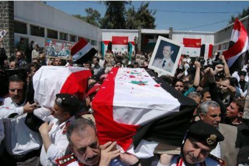 Syrian military police carry coffins as they prepare to send the bodies of 11 soldiers and security force members to their families for burial in the city of Homs.