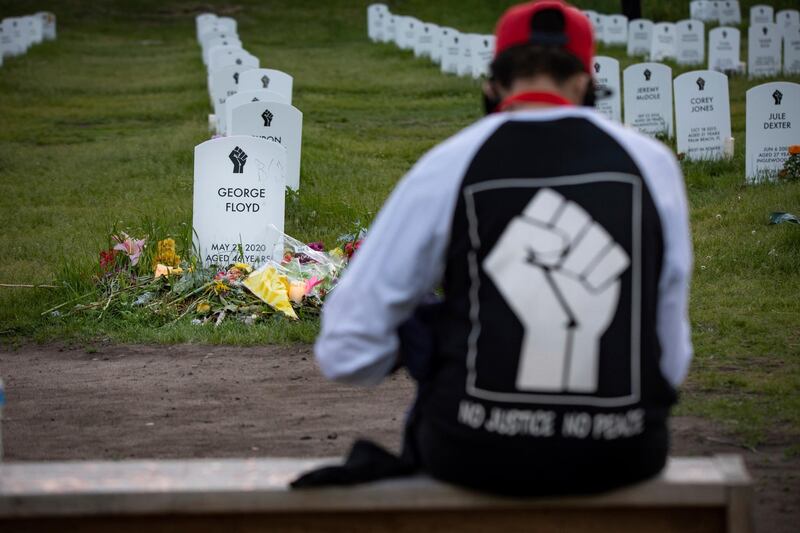 A man sits in front of the Say Their Names cemetery, close to George Floyd Square, in Minneapolis. AP