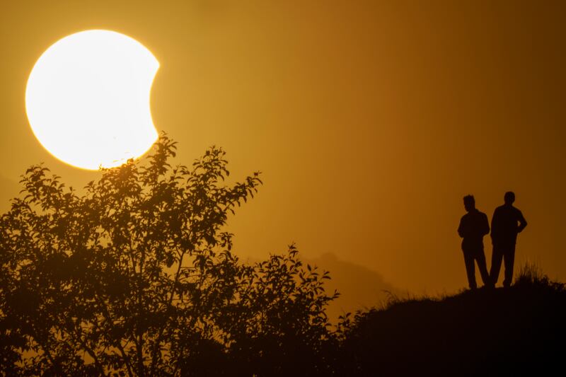 People are silhouetted against a partial solar eclipse seen from Kathmandu, Nepal. AP