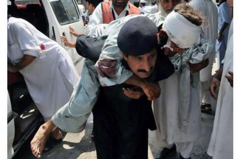 A Pakistani security guard helps an injured blast victim as he arrives at a hospital in Peshawar on Friday, July 9, 2010, following a suicide bomb attack in district of Mohmand.
