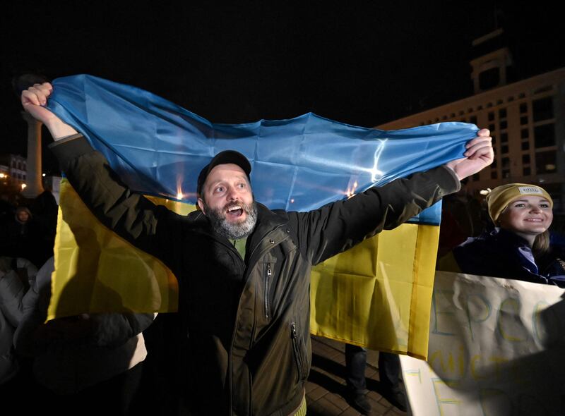 A man holds a Ukranian flag as people gather in Maidan Square to celebrate the liberation of Kherson, in Kyiv on November 11, 2022, amid the Russian invasion of Ukraine.  - Ukraine's President Volodymyr Zelensky said on November 11 that Kherson was "ours" after Russia announced the completion of its withdrawal from the regional capital, the only one Moscow captured in nearly nine months of fighting.  (Photo by Genya SAVILOV  /  AFP)