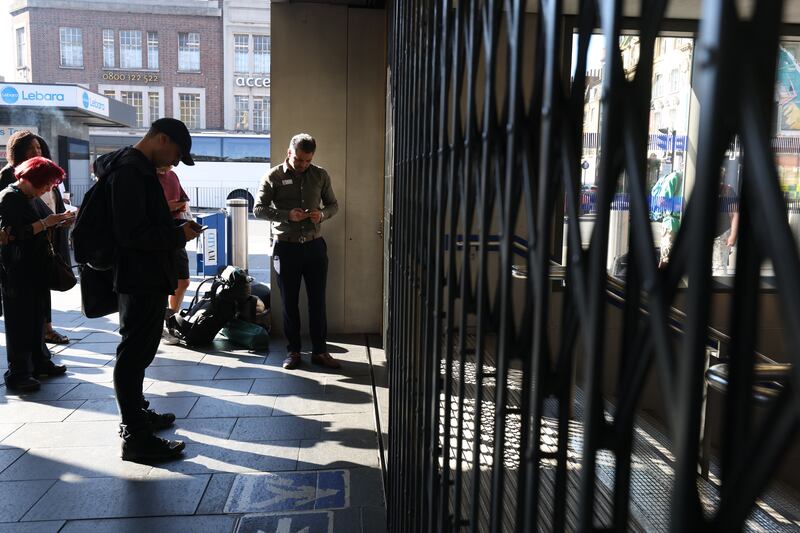 Passengers wait for Kings Cross St Pancras underground station in London to open. PA