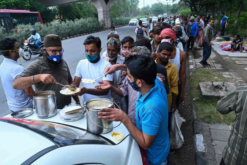 Homeless people mostly working as daily wage labourers and are out of jobs due to the lockdown queue up as volunteers distribute food along the roadside in New Delhi, India. AFP