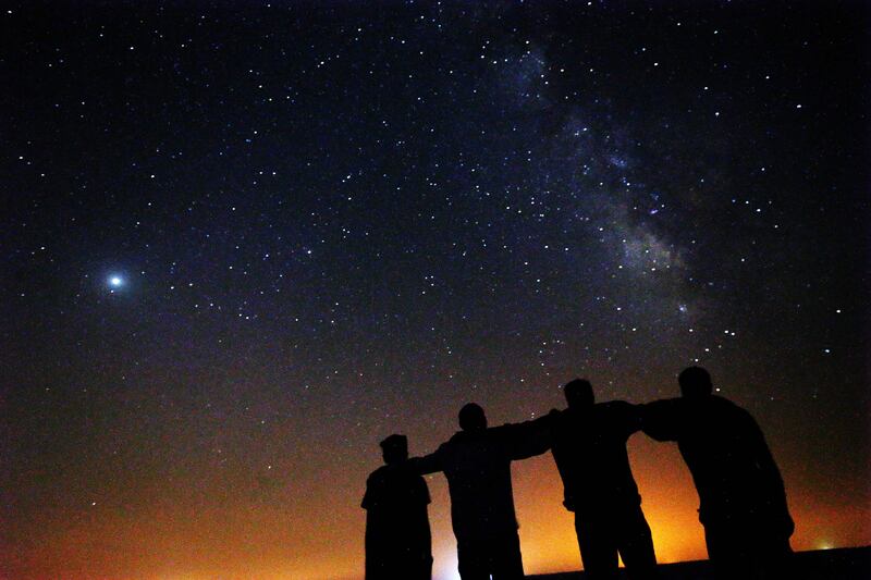 People watch as the stars light up the sky over the rolling sand dunes.