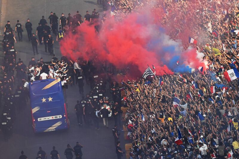 TOPSHOT - France's fans light flares as they greet France's national football team players as they parade on a bus down the Champs-Elysee in Paris, on July 16, 2018 after winning the Russia 2018 World Cup final football match. / AFP / Bertrand GUAY
