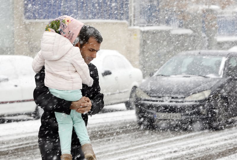 A man and child pick their way through traffic in heavy snowfall in Tehran. EPA