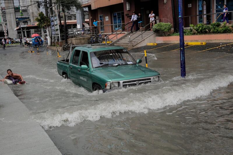 A motorist wades through a flooded road in Makati, south of Manila, Philippines. EPA