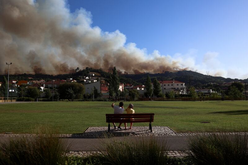 People watch as smoke rises from a wildfire in Venda do Pinheiro, Portugal. Reuters