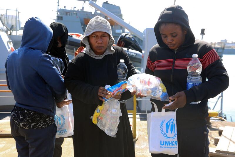 Rescued migrants receive food aid as they leave a coastguard vessel in Tripoli, Libya. AFP