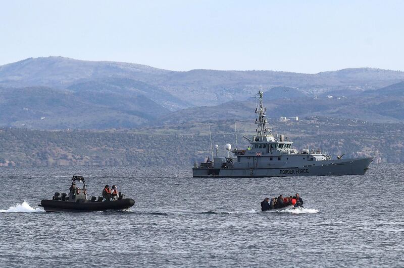 A dinghy with 15 Afghan refugees, 5 children, 3 women and 7 men, approaches the Greek island of Lesbos on February 28, 2020 next to UK Border Force patrol boat HMC Valiant (background), a cutter patroling in Agean sea under European Union border force Frontex. - Turkey will no longer close its border gates to refugees who want to go to Europe, a senior official told AFP on February 28, shortly after the killing of 33 Turkish soldiers in an airstrike in northern Syria. (Photo by ARIS MESSINIS / AFP)