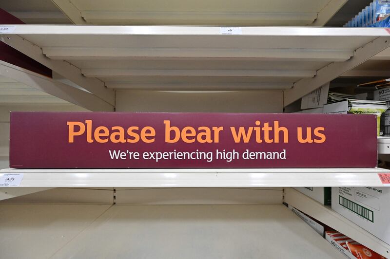 A sign requesting shoppers' patience about out-of-stock products on empty shelves in a supermarket at Nine Elms, south London. AFP
