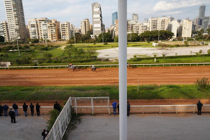 Horses race to the finish line in front of the grandstand.