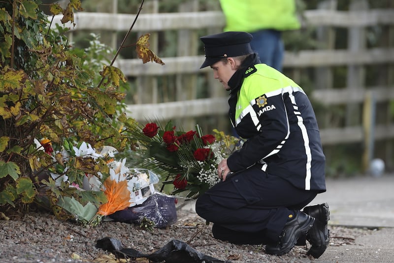 An Irish police officer lays flowers she was given by a member of the public at the scene of the explosion. PA