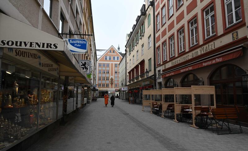 Two people walk along an empty street where the shops and restaurants are closed, in Munich, southern Germany. AFP