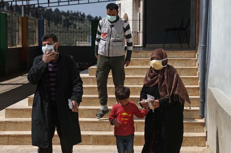 Displaced Syrians wear protective masks as they leave a lecture provided by staff from Turkey's Humanitarian Relief Foundation to raise awareness about the coronavirus pandemic at a refugee camp in Kafr Lusin, Syria, on March 23, 2020. AFP