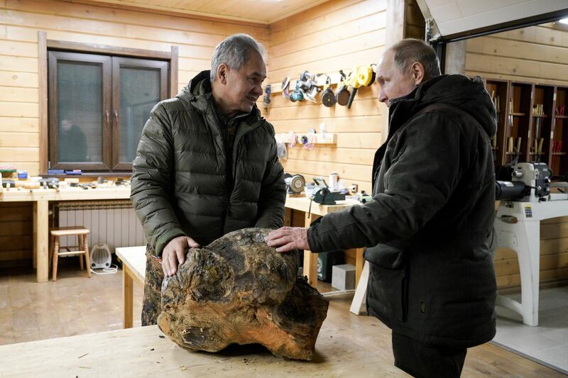 Russian Defence Minister Sergei Shoigu and Russian President Vladimir Putin chat as they examine a piece of wood for crafting, at Mr Shoigu's workshop, in the Siberian taiga. AP Photo