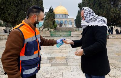A volunteer sprays sanitising gel on the hands of a Palestinian man on his way to perform Friday prayers in the nearly deserted Al-Aqsa mosque compound in the Old City of Jerusalem, after clerics took protective measures and ordered the mosques shut in a bid to stem the spread of the novel coronavirus, on March 20, 2020. Israel has 433 confirmed cases of COVID-19, with another 44 in the occupied Palestinian territories and tens of thousands in self-isolation. / AFP / AHMAD GHARABLI
