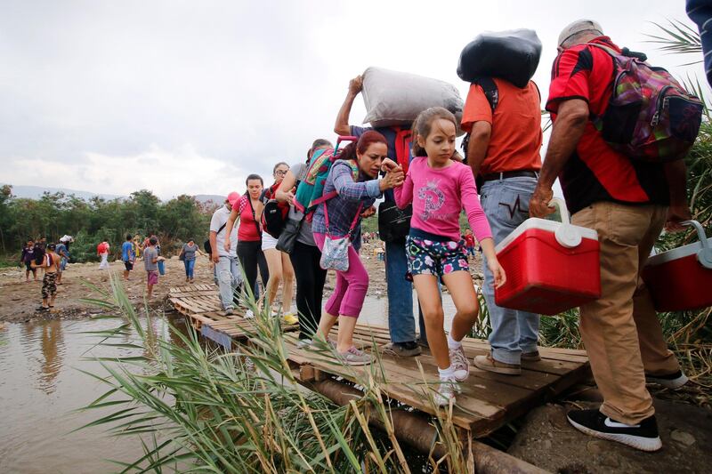 People cross a makeshift bridge in the Tachira River, from Venezuela into Colombia, near the Simon Bolivar International bridge which Venezuelan authorities only open to students and the sick in Cucuta, Colombia, Tuesday, March 12, 2019, on the border with Venezuela. People crossing the river are using makeshift bridges as the water level grows with the approaching rainy season.  (AP Photo/Schneyder Mendoza)