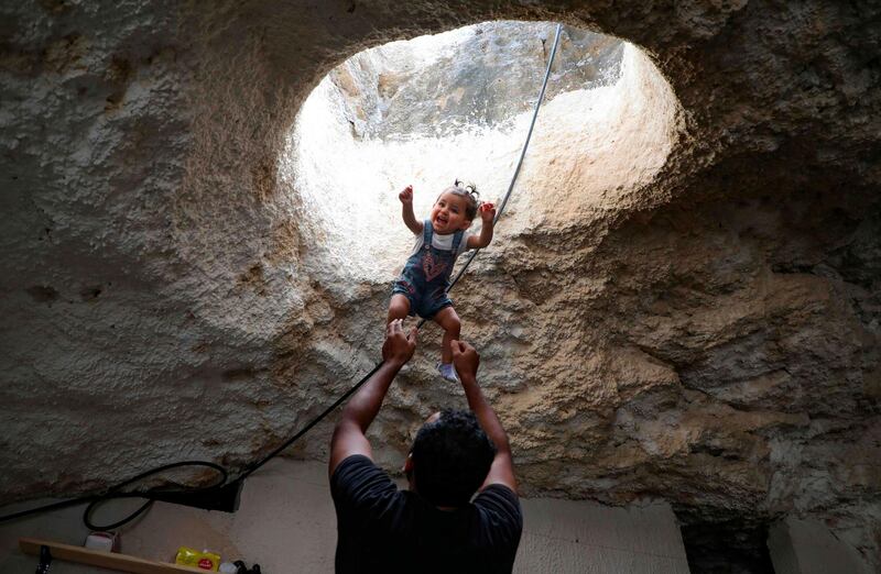 Ahmed Amarneh throws his daughter beneath a skylight hole as they play together at his home. AFP