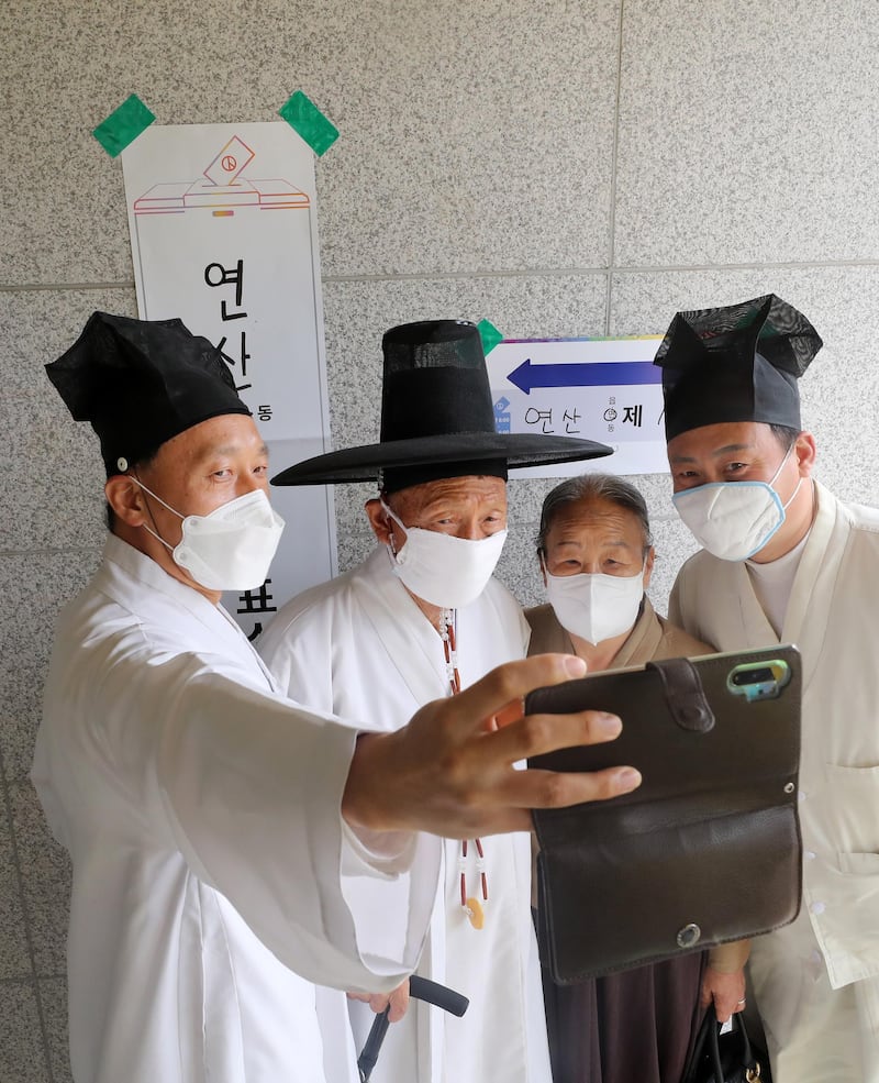 Clad in a dopo, a traditional men's outfit, Yoo Bok-yeop (2-L), a senior teacher of Yangji Village School, and his family members photograph themselves after casting their ballots. EPA