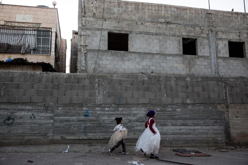 Young bedouin girls wearing party dresses as they walk along a road by unfinished homes in Rahat ,the the largest Bedouin township in Israel . The residents of Rahat are connected to their basic needs unlike those living in  unrecognized illegal villages with scarce access to water, electricity and other services. (Photo by Heidi Levine for The National).