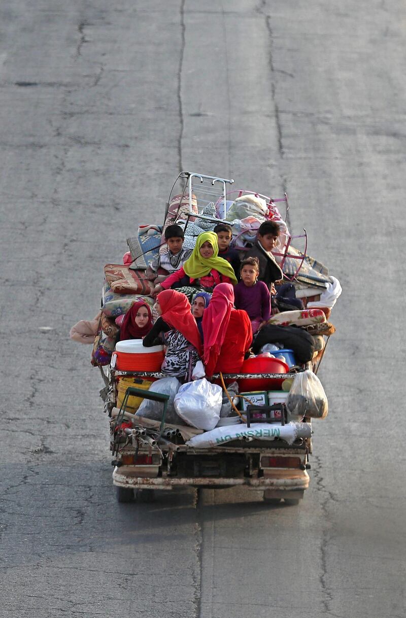 Syrian families from the southeastern Idlib province and the northern countryside of Hama fleeing battles with trucks loaded with their belongings, drive past a flock of sheep on the highway, as they drive near Maaret al-Numan in the southern Idlib province.  AFP