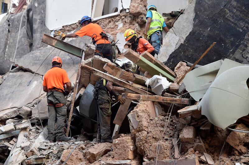 Onlookers gather as rescue workers dig through the rubble of a badly damaged building in  Lebanon's capital Beirut in search of possible survivors from a mega-blast at the adjacent port one month ago. EPA
