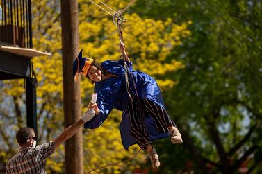 A graduate zip lines from the school to the stage where she grabs her diploma from the head administrator. Celebrating achievements is more important amid the fallout from the pandemic. AP