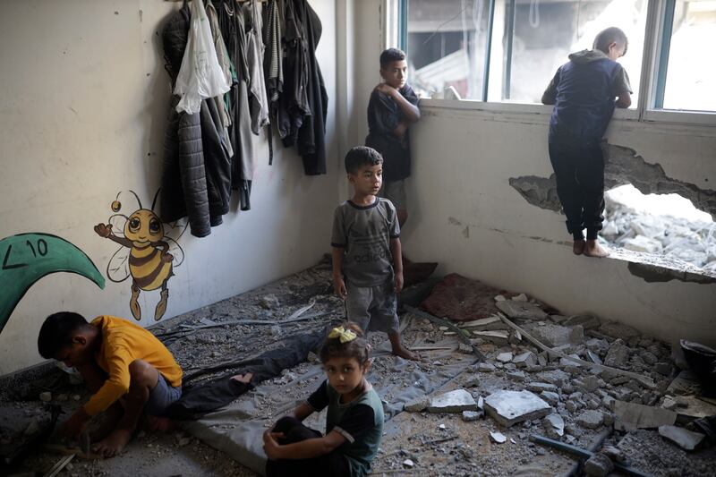 Palestinian children inspect heavy damage to an UNRWA-run school sheltering displaced people the day after a nearby house was targeted by Israeli bombardment in Khan Younis. AP