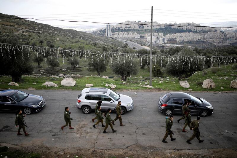 Jewish settlement of Har Homa is seen in the background as Israeli soldiers walk next to the convoy of Pierbattista Pizzaballa, the acting Latin Patriarch of Jerusalem, as it makes its way from Jerusalem into the West Bank town of Bethlehem for Christmas celebrations December 24, 2018. REUTERS/Amir Cohen