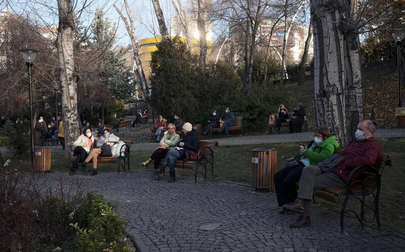 People, wearing masks to help protect against the spread of coronavirus, rest in a public garden hours before a two-day weekend curfew, in Ankara, Turkey. AP