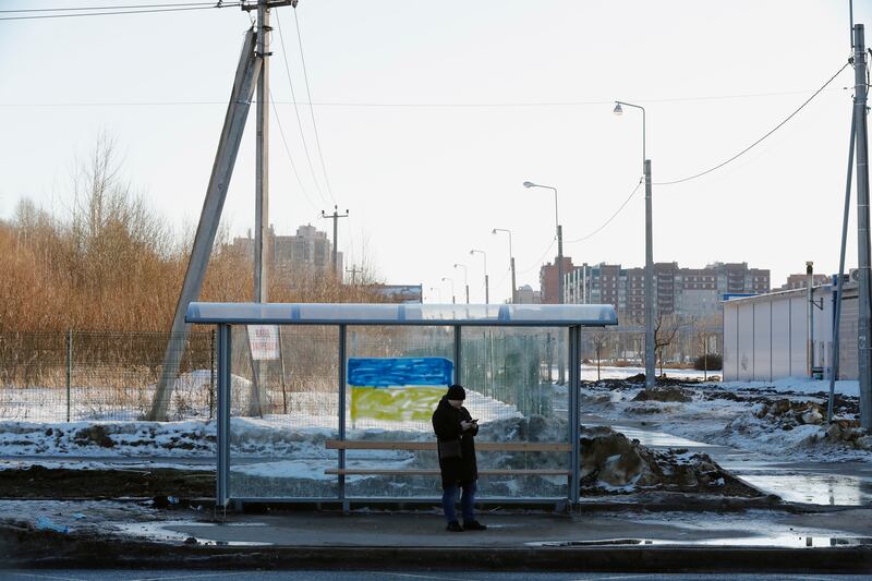 A man waits at a bus stop in St Petersburg, which has been with a painted in the colours of Ukraine's national flag. EPA